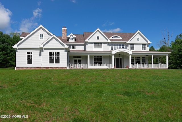 view of front facade featuring a front yard, a chimney, and covered porch