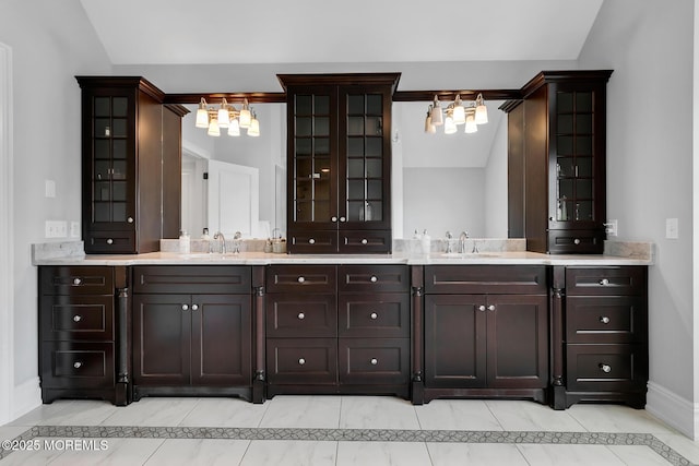bathroom with a chandelier, baseboards, double vanity, inlaid floor details, and tile patterned flooring