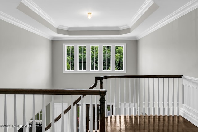 staircase featuring a raised ceiling and crown molding