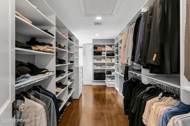 walk in closet with attic access and wood finished floors