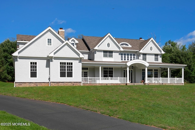 view of front of house with covered porch, a front lawn, and a chimney