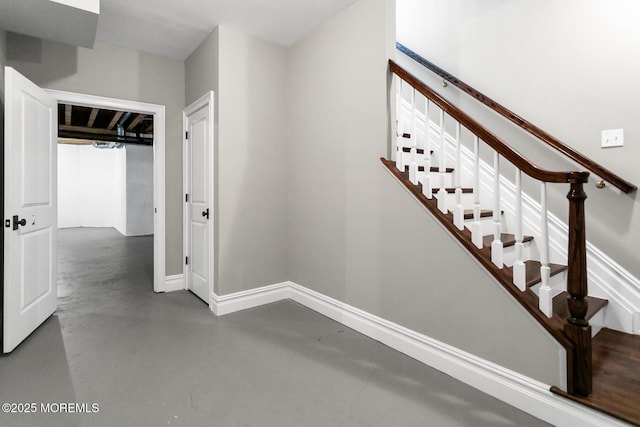 stairway featuring concrete flooring and baseboards