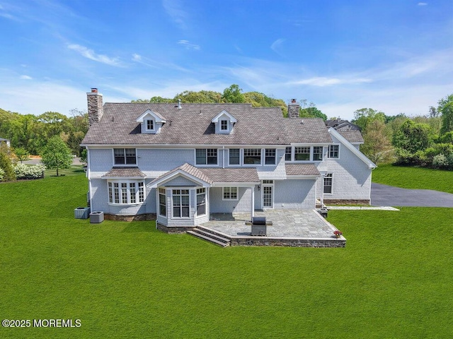 back of house featuring a patio area, a chimney, a yard, and central air condition unit