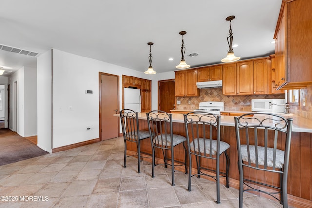 11 S Point Ct, Toms River, NJ 08757 - kitchen with under cabinet range hood, white appliances, decorative backsplash, light countertops, and a peninsula