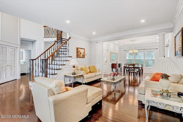 living room featuring decorative columns, dark wood finished floors, crown molding, stairs, and recessed lighting