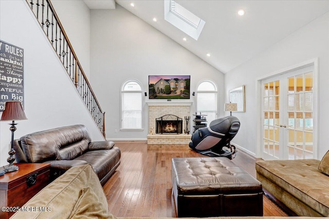 living room featuring high vaulted ceiling, recessed lighting, hardwood / wood-style floors, a brick fireplace, and baseboards