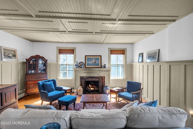 58 River Ave, Island Heights, NJ 08732 - living area featuring a fireplace, a decorative wall, a wainscoted wall, a baseboard heating unit, and light wood-style flooring