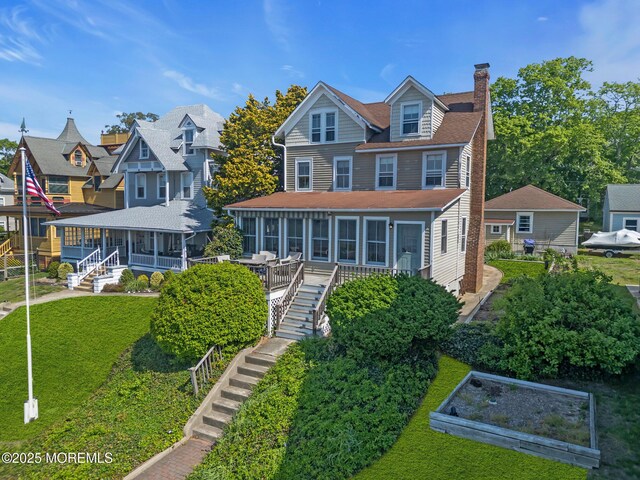 58 River Ave, Island Heights, NJ 08732 - back of property featuring a sunroom, stairs, a chimney, a vegetable garden, and a lawn