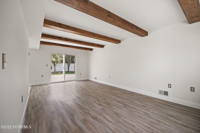 spare room featuring baseboards, wood finished floors, and beam ceiling