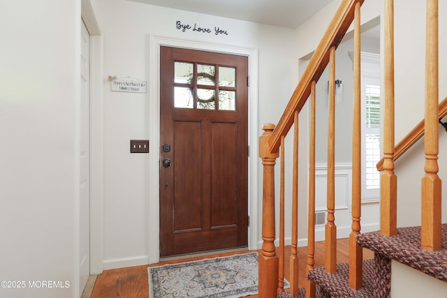 entrance foyer with stairs, plenty of natural light, and wood finished floors
