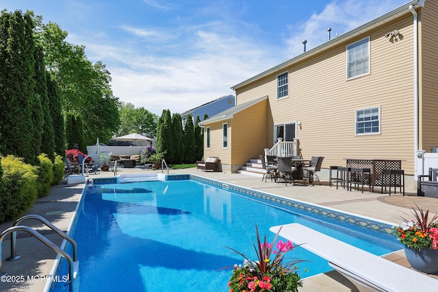 swimming pool with a diving board and a patio