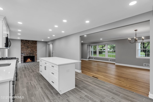 92 Sargent Rd, Freehold, NJ 07728 - kitchen with open floor plan, light wood-style floors, a brick fireplace, light countertops, and recessed lighting