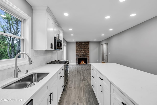 92 Sargent Rd, Freehold, NJ 07728 - kitchen with appliances with stainless steel finishes, a sink, wood finished floors, a fireplace, and light countertops