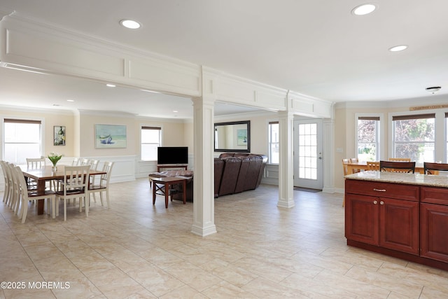 kitchen featuring ornate columns, crown molding, a decorative wall, recessed lighting, and light stone countertops