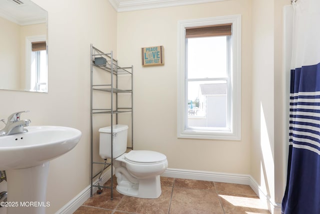 bathroom featuring crown molding, baseboards, toilet, and a sink