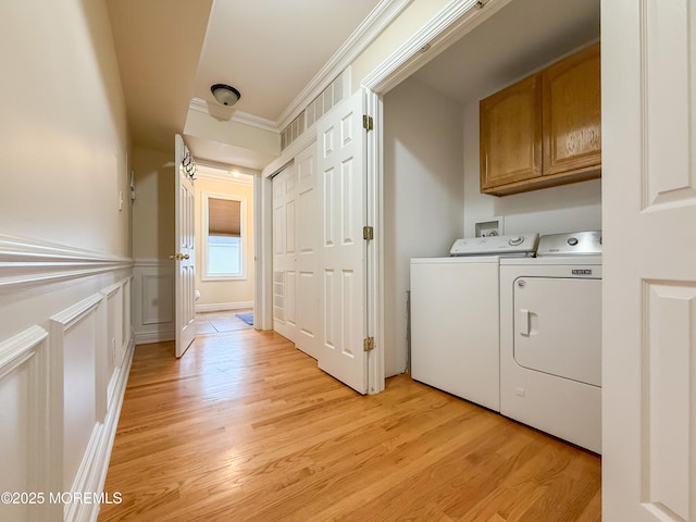 laundry area with cabinet space, separate washer and dryer, light wood-type flooring, and ornamental molding