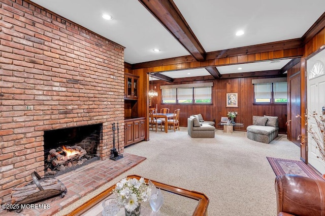 carpeted living room featuring beamed ceiling, wooden walls, a brick fireplace, and recessed lighting
