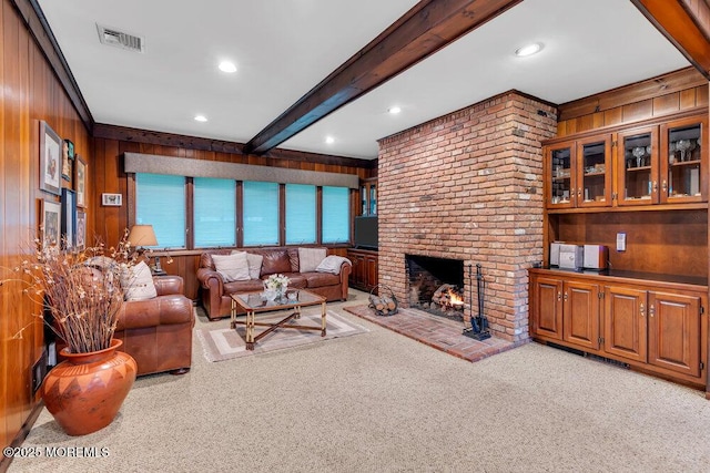 living room featuring wood walls, light colored carpet, a brick fireplace, beam ceiling, and recessed lighting