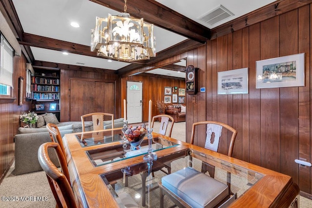 dining area featuring wood walls, beam ceiling, a chandelier, and carpet floors