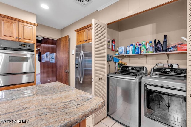 clothes washing area with washing machine and clothes dryer and light tile patterned floors