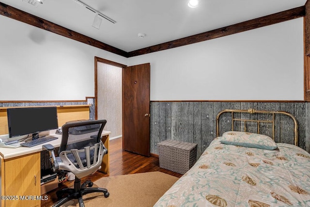 bedroom with a wainscoted wall, wood finished floors, and a desk