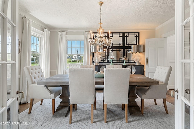 dining space with a chandelier, a textured ceiling, and ornamental molding