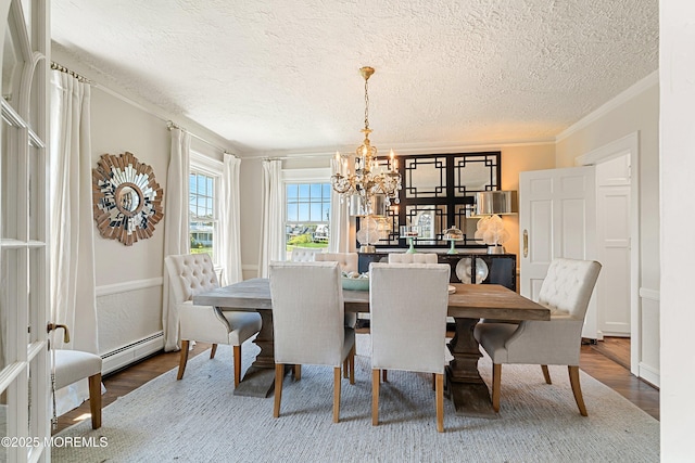 dining room featuring a chandelier, baseboard heating, wood finished floors, a textured ceiling, and crown molding