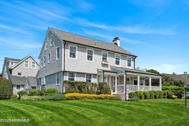view of front of house featuring covered porch, a chimney, and a front yard