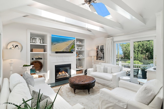 living room with a glass covered fireplace, a skylight, and built in shelves