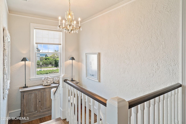 stairway featuring a textured wall, a chandelier, crown molding, and wood finished floors