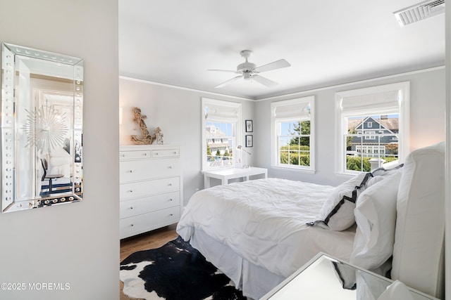 bedroom featuring dark wood finished floors, ornamental molding, and a ceiling fan