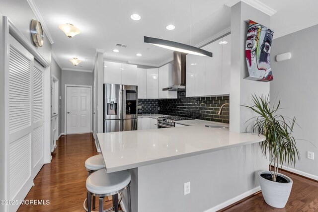 7 Samantha Dr, Tinton Falls, NJ 07712 - kitchen featuring wall chimney range hood, appliances with stainless steel finishes, modern cabinets, white cabinets, and a peninsula