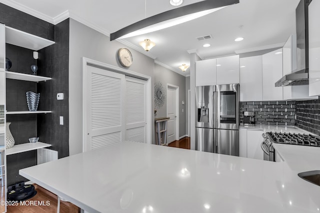 7 Samantha Dr, Tinton Falls, NJ 07712 - kitchen featuring appliances with stainless steel finishes, ornamental molding, light countertops, wall chimney range hood, and white cabinetry