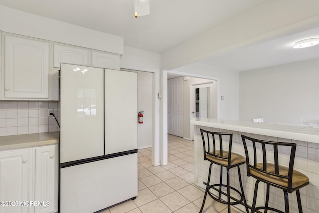 1164B Argyll Cir, Lakewood, NJ 08701 - kitchen with freestanding refrigerator, white cabinetry, light countertops, tasteful backsplash, and light tile patterned floors