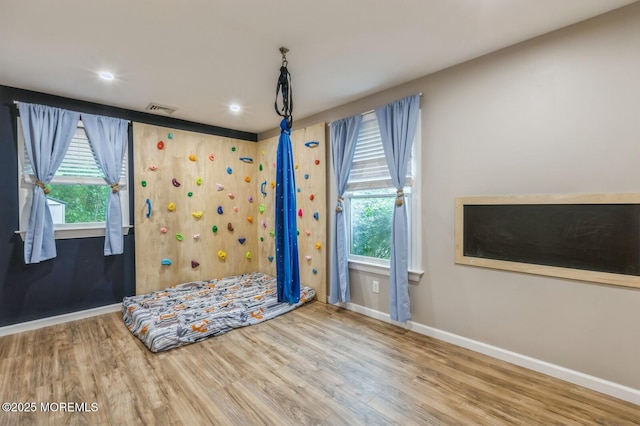 empty room with baseboards, wood finished floors, plenty of natural light, and recessed lighting