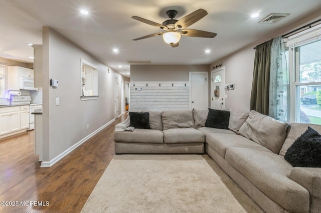 living room featuring wood finished floors, a ceiling fan, recessed lighting, and baseboards