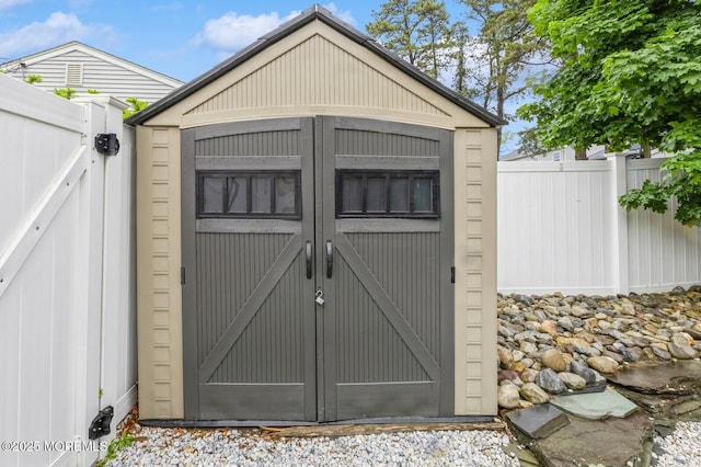view of shed featuring fence and a gate