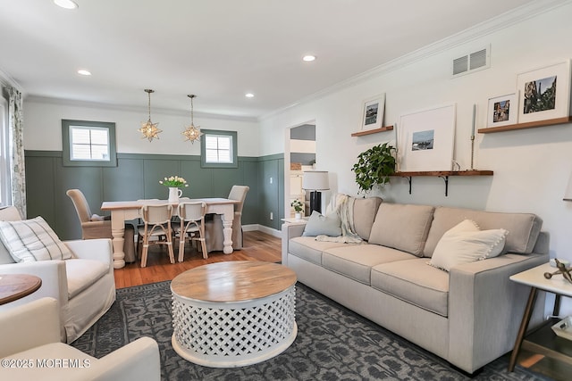 living room with wood finished floors, wainscoting, ornamental molding, and recessed lighting