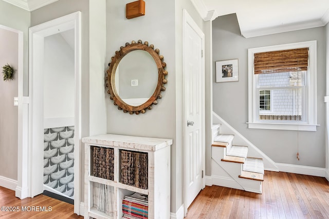 hallway featuring hardwood / wood-style flooring, baseboards, crown molding, and stairs