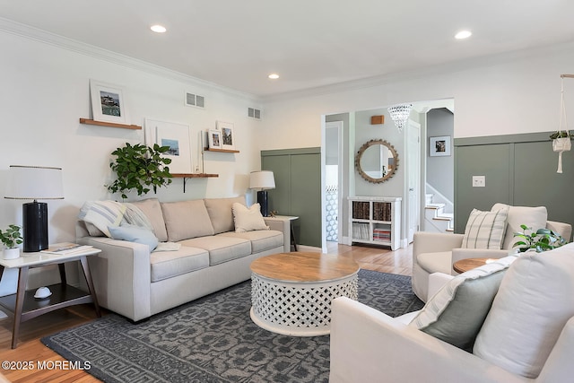 living area featuring wood finished floors, ornamental molding, stairs, and recessed lighting