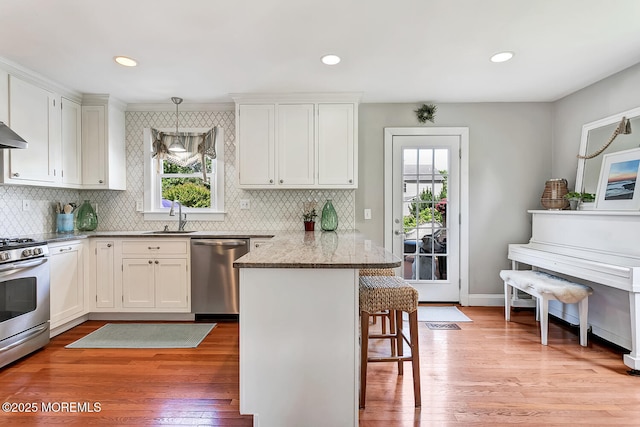 kitchen featuring appliances with stainless steel finishes, a breakfast bar, a peninsula, plenty of natural light, and recessed lighting