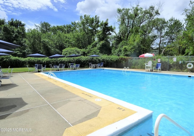 community pool with fence and a patio area