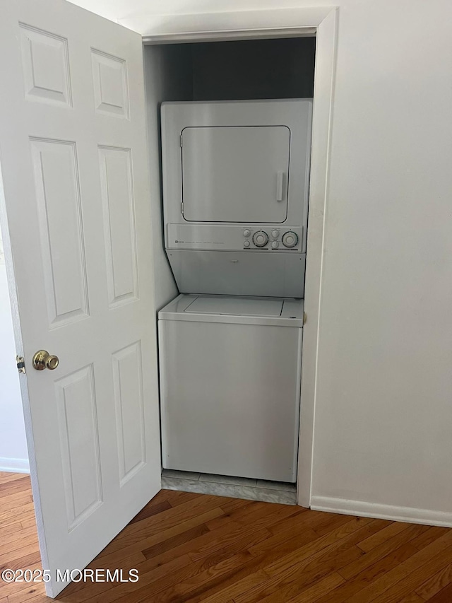 washroom with stacked washer and clothes dryer, light wood-type flooring, and baseboards