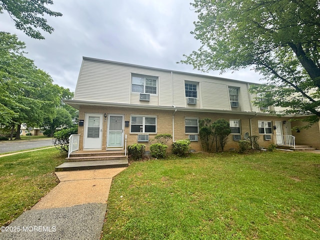 multi unit property featuring a front lawn, cooling unit, and brick siding