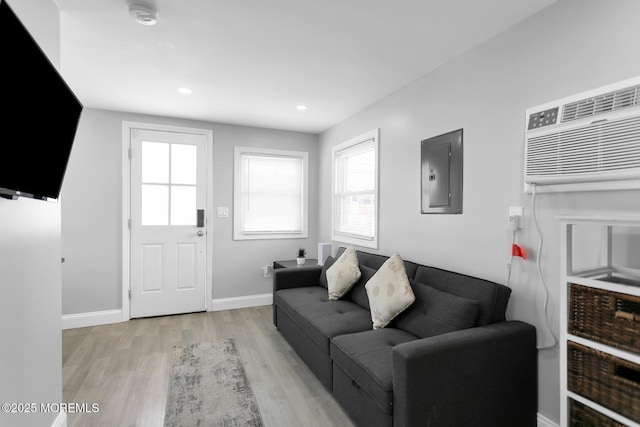 living area featuring electric panel, light wood finished floors, baseboards, and recessed lighting