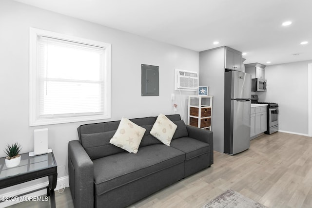 living area with electric panel, light wood-style flooring, a wall mounted air conditioner, recessed lighting, and baseboards