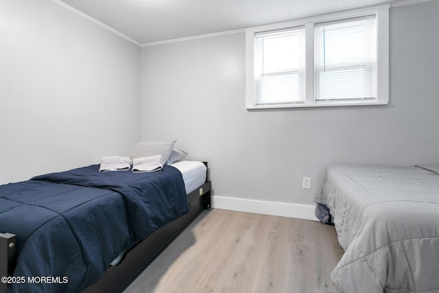 bedroom featuring wood finished floors, a textured ceiling, baseboards, and ornamental molding
