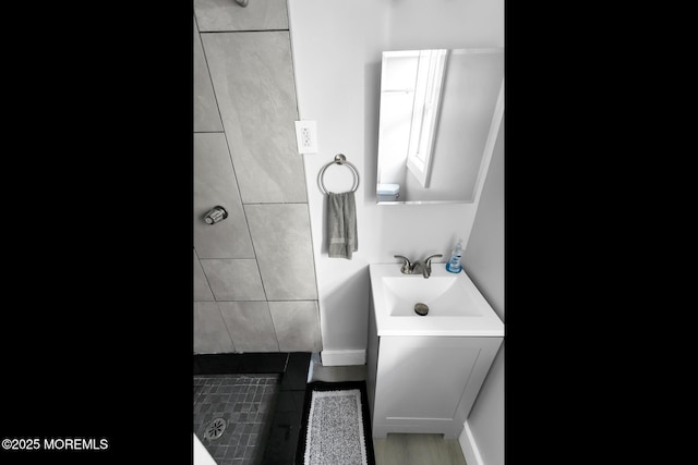 bathroom with a tile shower and vanity