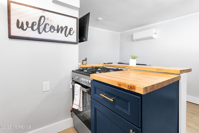 kitchen with gas range, blue cabinets, wood counters, a wall mounted air conditioner, and baseboards