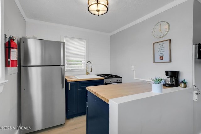 kitchen with freestanding refrigerator, blue cabinetry, crown molding, stove, and light wood-type flooring